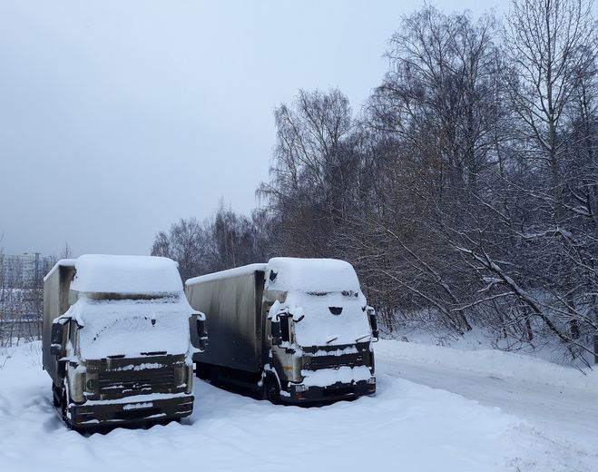 Два грузовика стоят под снегом в январе 2019