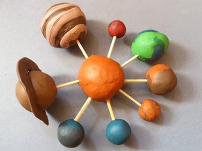 макет солнечной системой вместе с ребенком из пластилина